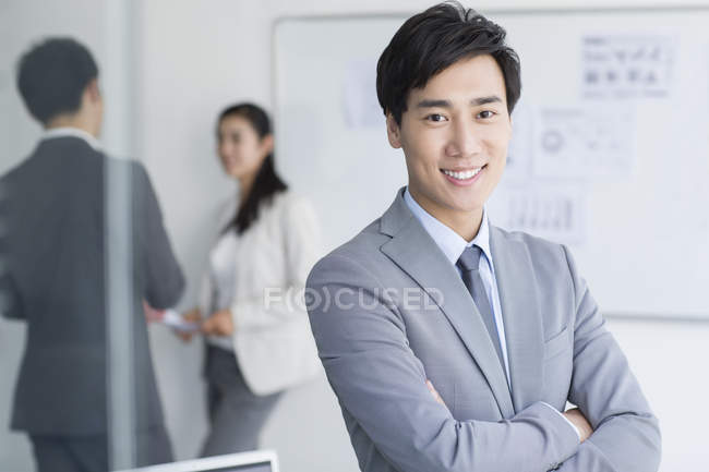 Chinese businessman standing with arms folded — Stock Photo
