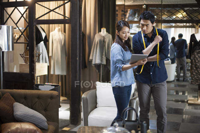 Chinese fashion designers using digital tablet in shop — Stock Photo