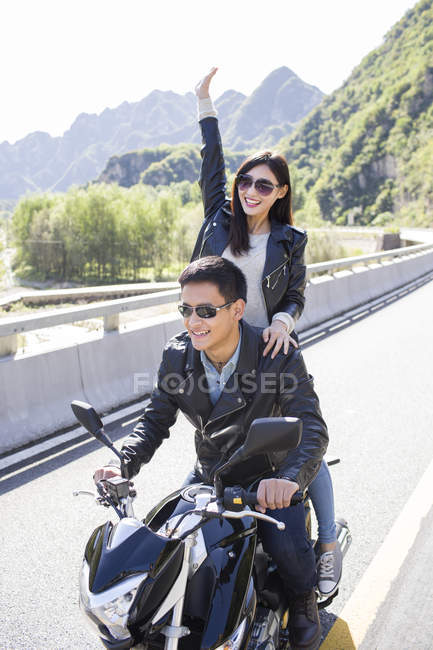 Chinese couple riding motorcycle together — Stock Photo