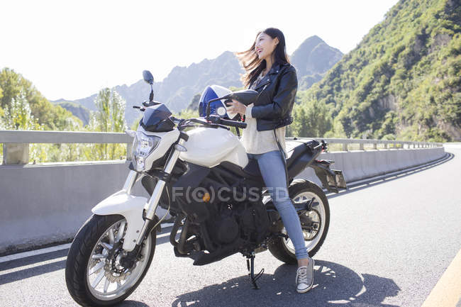 Китаянка, сидящая на мотоцикле со шлемом — стоковое фото