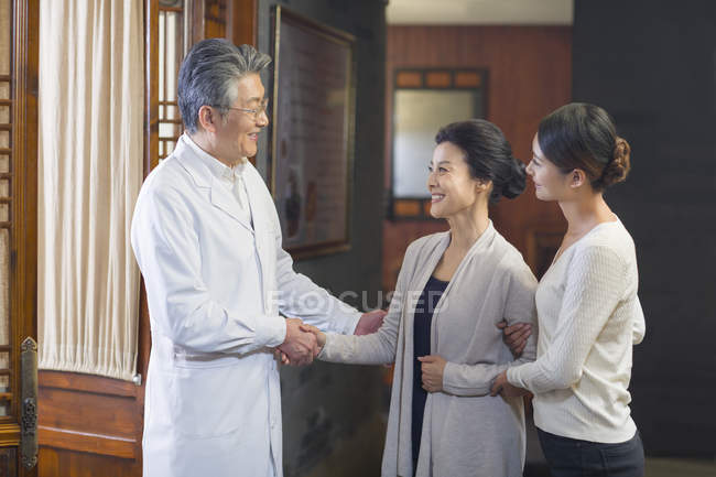 Médico chino dando la mano a los pacientes en la sala del hospital - foto de stock