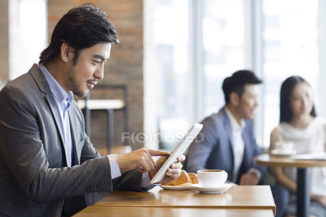 Homme d'affaires chinois utilisant une tablette numérique dans un café — Photo de stock