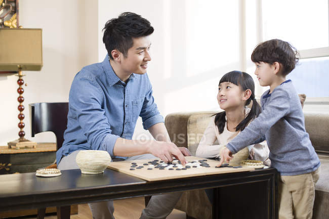 Chinese father explaining children game of Go — Stock Photo