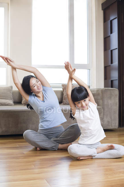 Китайская мать и дочь практикуют йогу в гостиной — стоковое фото