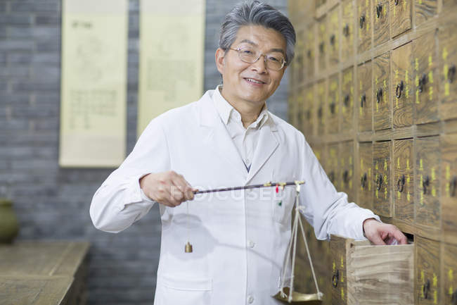 Farmacista cinese in piedi con bilancia a cassetto aperto — Foto stock