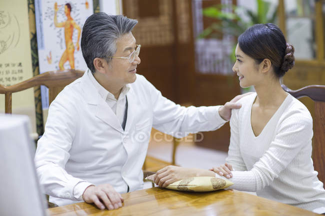 Médico chino senior hablando con paciente femenino - foto de stock