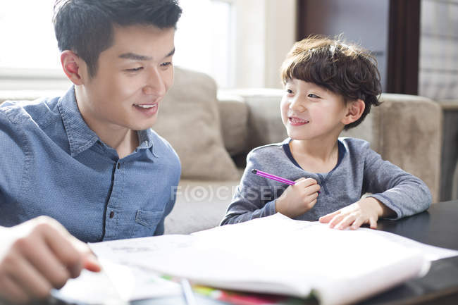 Padre chino ayudando a su hijo con la tarea - foto de stock