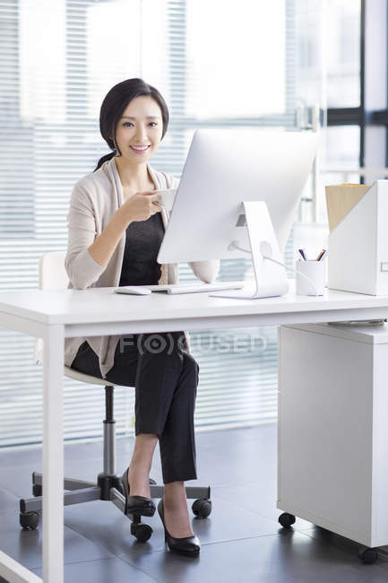 Donna cinese che beve caffè sul posto di lavoro — Foto stock