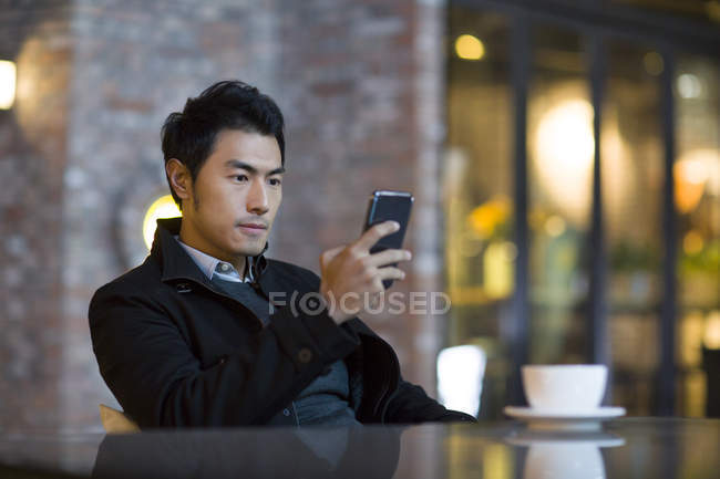 Homem chinês usando smartphone no café da cidade — Fotografia de Stock