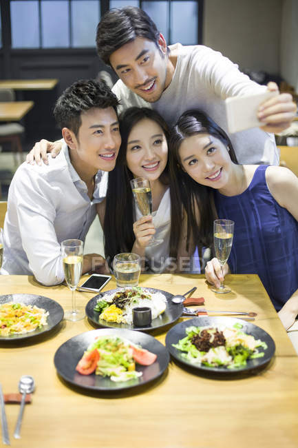 Amici che scattano selfie con smartphone nel ristorante — Foto stock