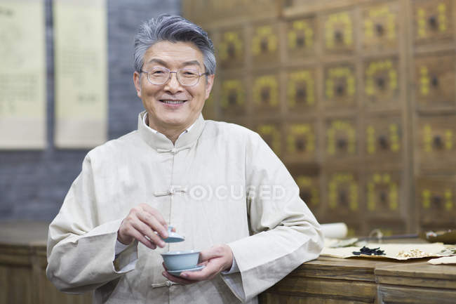 Senior Chinese man holding cup of tea — Stock Photo