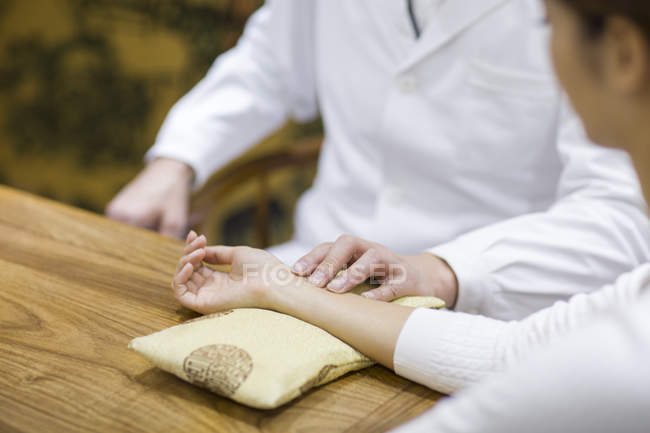 Male doctor taking pulse of patient — Stock Photo