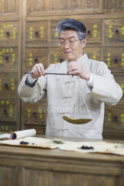 Chinese pharmacist working with weight scale in pharmacy — Stock Photo