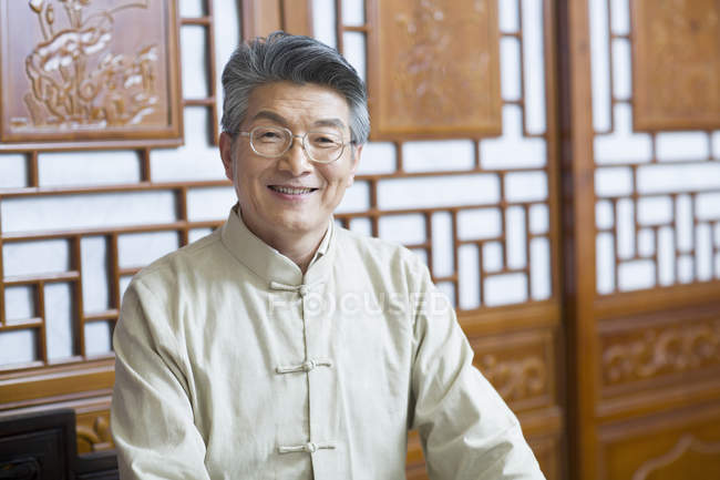 Retrato de homem chinês sênior olhando na câmera no interior tradicional — Fotografia de Stock