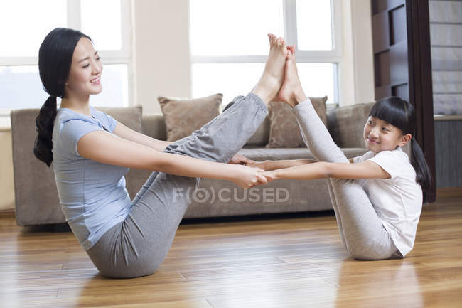 Mère et fille chinoises pratiquant le yoga dans le salon — Photo de stock