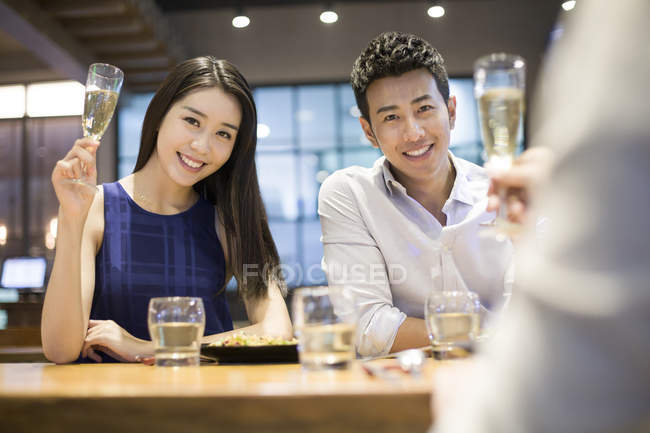 Amigos chinos animando con champán en restaurante - foto de stock