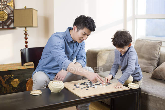 Chinese father and son playing game of Go at home — Stock Photo