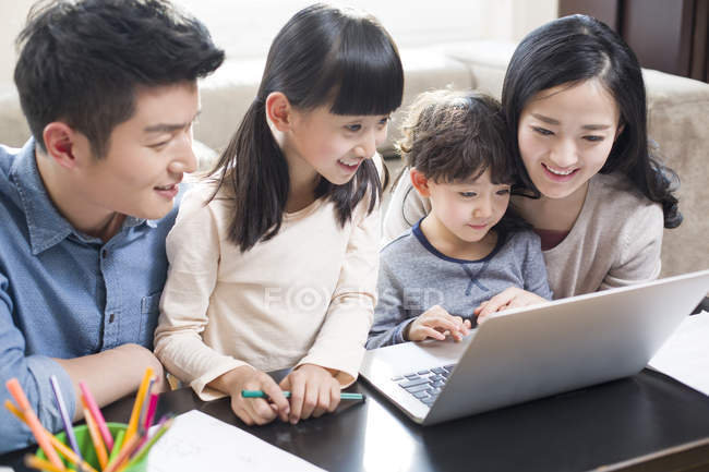 Chinese parents with kids using laptop in living room — Stock Photo