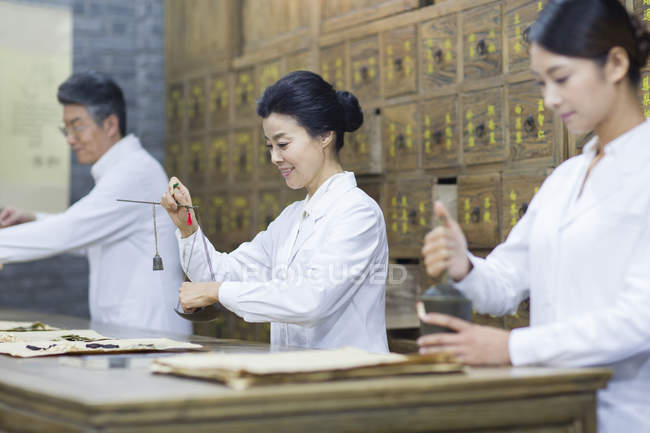 Médicos chinos trabajando en farmacia tradicional - foto de stock