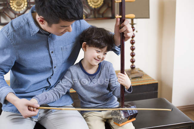 Китайский отец обучает сына традиционному музыкальному инструменту erhu — стоковое фото