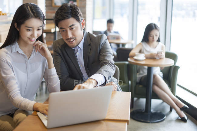 Chinese business people working with laptop in cafe — Stock Photo