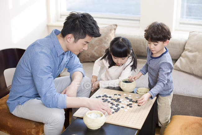 Chinese children playing the game of Go with father — Stock Photo