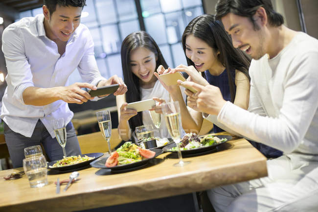 Amis chinois prenant des photos de nourriture au restaurant — Photo de stock