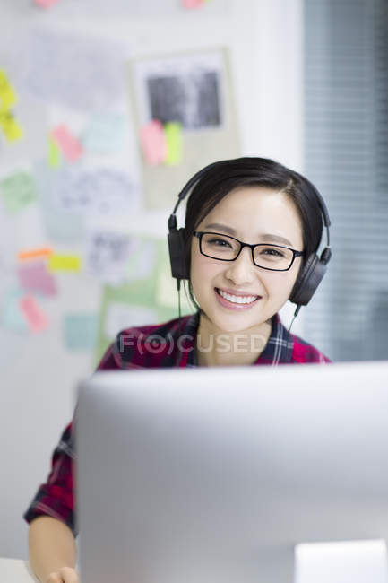 Mulher chinesa ouvindo música no escritório — Fotografia de Stock