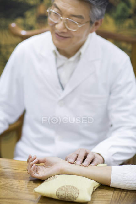 Médico chinês sênior tomando pulso de paciente do sexo feminino — Fotografia de Stock