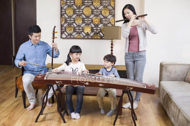 Família chinesa tocando instrumentos musicais tradicionais em casa — Fotografia de Stock