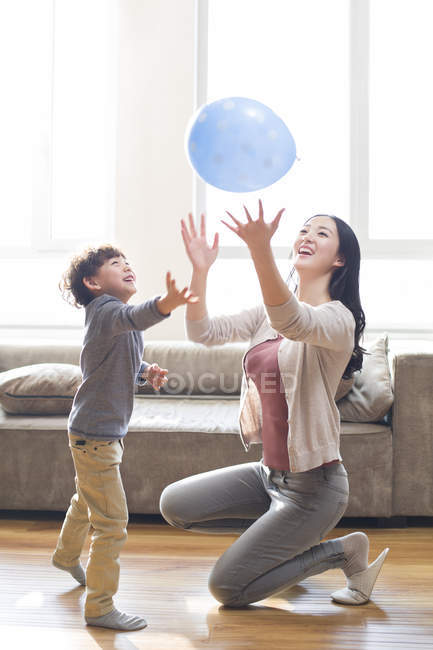 Chinese mother and son playing with balloon at home — Stock Photo