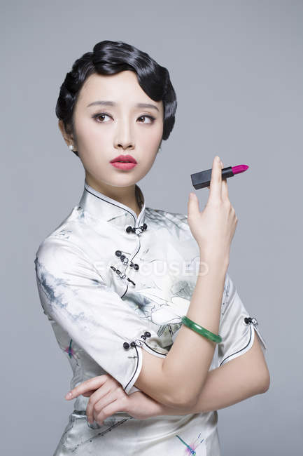Femme chinoise en robe traditionnelle tenant rouge à lèvres — Photo de stock