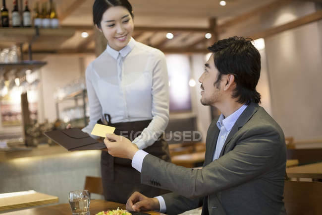 Homem chinês dando cartão de crédito garçonete — Fotografia de Stock
