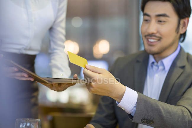 Chino hombre dando camarera tarjeta de crédito - foto de stock