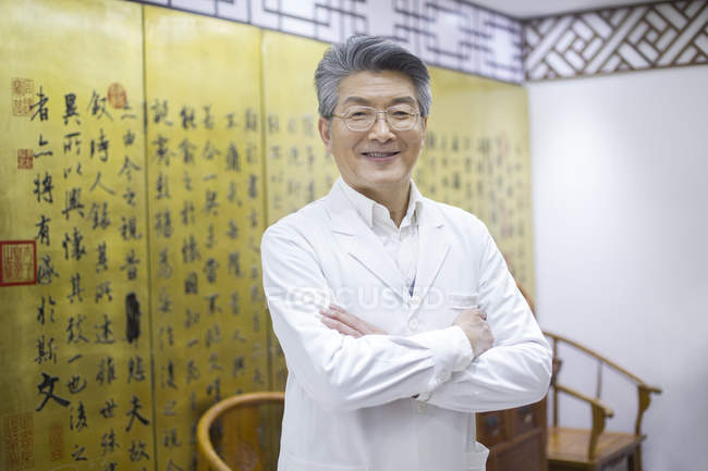 Старший китайський лікар, стоячи з руки складені — стокове фото