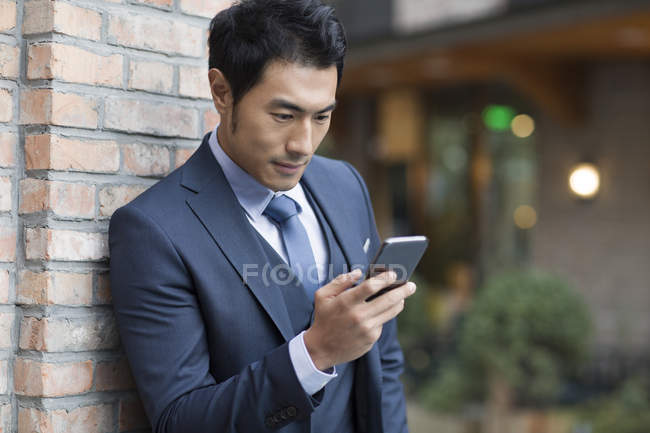 Empresário chinês usando smartphone na rua — Fotografia de Stock