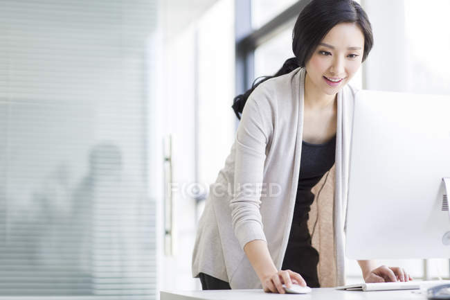 Chinesin steht und benutzt Computer im Büro — Stockfoto