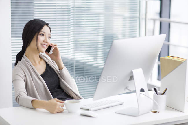 Donna cinese che parla al telefono sul posto di lavoro — Foto stock