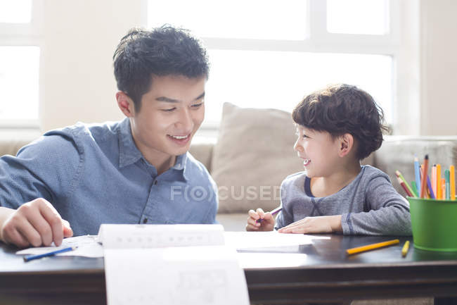 Padre e hijo chinos haciendo tarea juntos - foto de stock