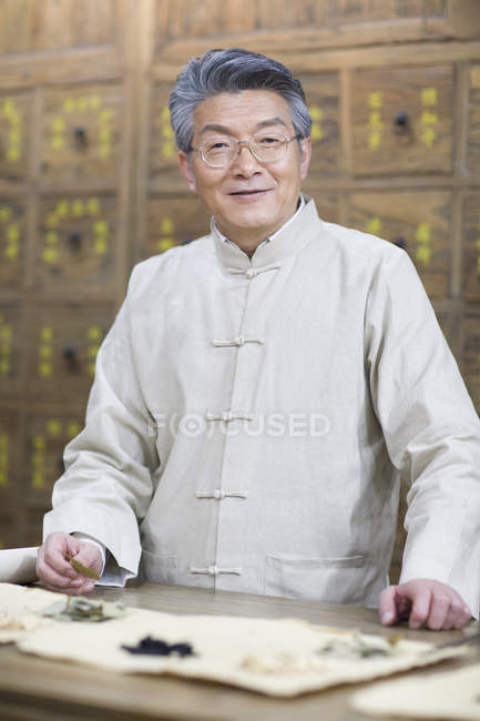 Chinese doctor with various medicinal herbs in pharmacy — Stock Photo