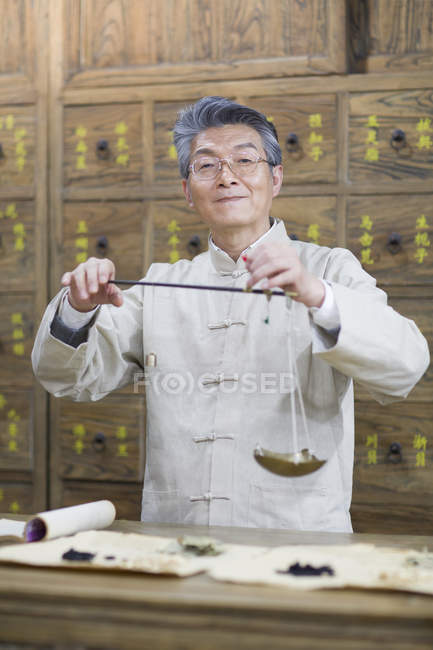 Chinese pharmacist standing with weight scale in pharmacy — Stock Photo