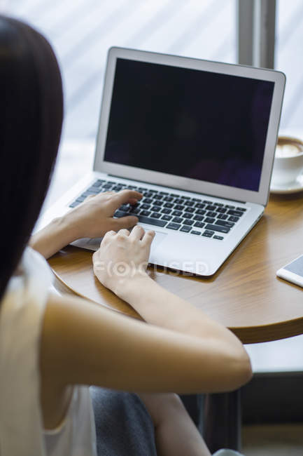 Жінка працює з ноутбуком в кафе, вид ззаду — стокове фото