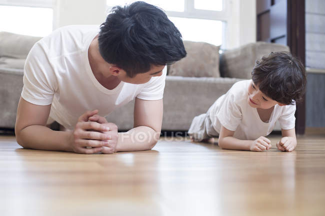 Chinês pai e filho praticando prancha posar em casa — Fotografia de Stock