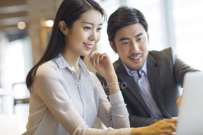 Uomo e donna cinese che utilizzano il computer portatile in caffè — Foto stock
