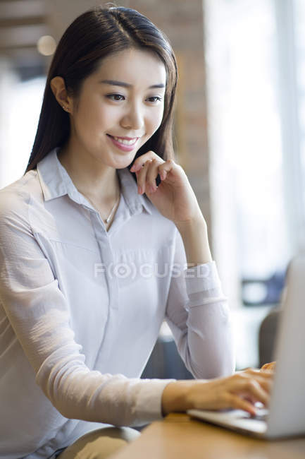 Chinese woman working with laptop in cafe — Stock Photo