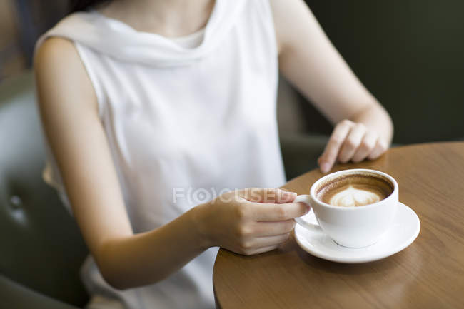 Mujer elegante sentada con café en la cafetería - foto de stock