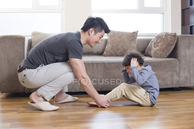 Chinese father helping son exercising at home — Stock Photo