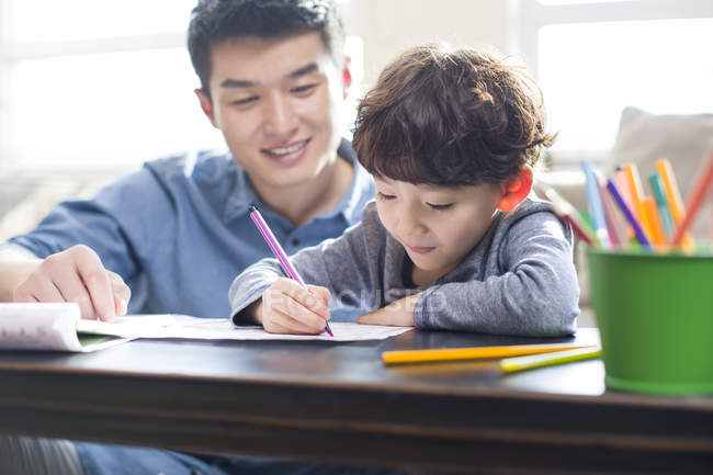 Chinese son doing homework with father — Stock Photo