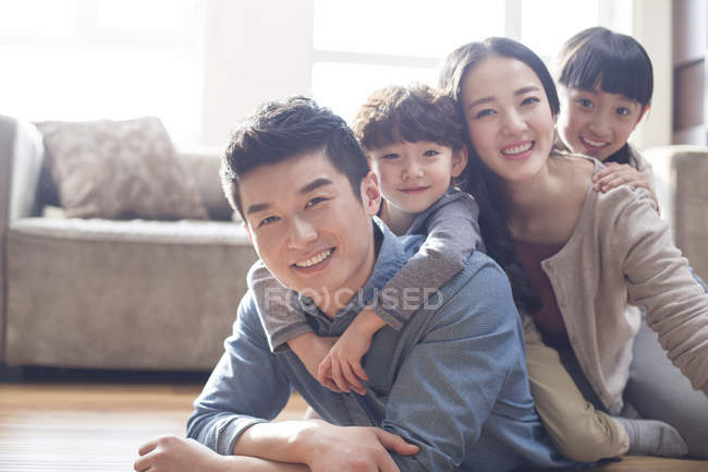 Retrato de la familia china acostada en el piso de la habitación - foto de stock