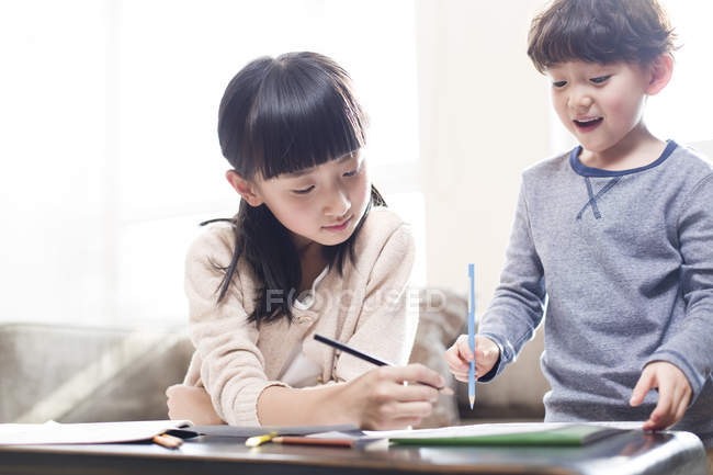 Chica china ayudando a chico a estudiar en casa - foto de stock